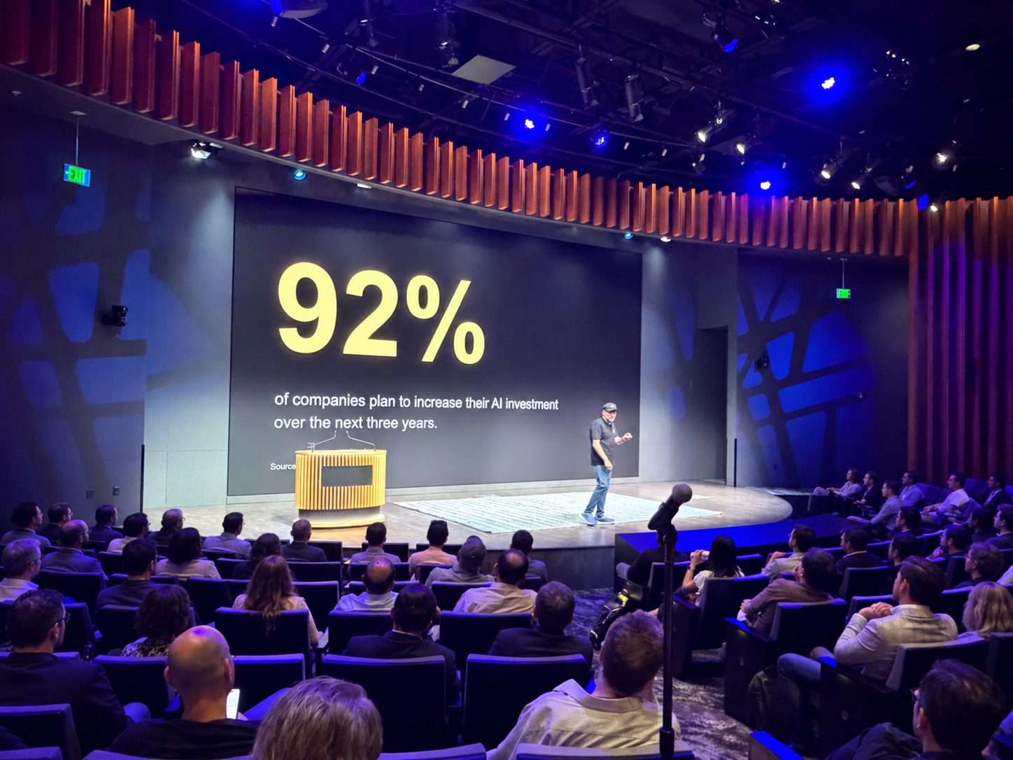 A speaker presenting AI investment statistics to an Open Future Forum audience